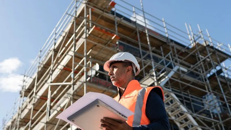 Albañil revisando el presupuesto de una obra junto al andamio de una vivienda en Murcia