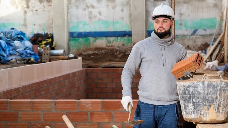 Albañil levantando un muro de ladrillo en una obra en Murcia